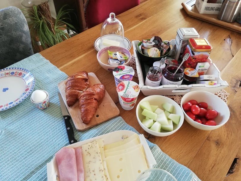 Ontbijttafel met croissants, kaas, ham, fruit en zelfgemaakte jam
