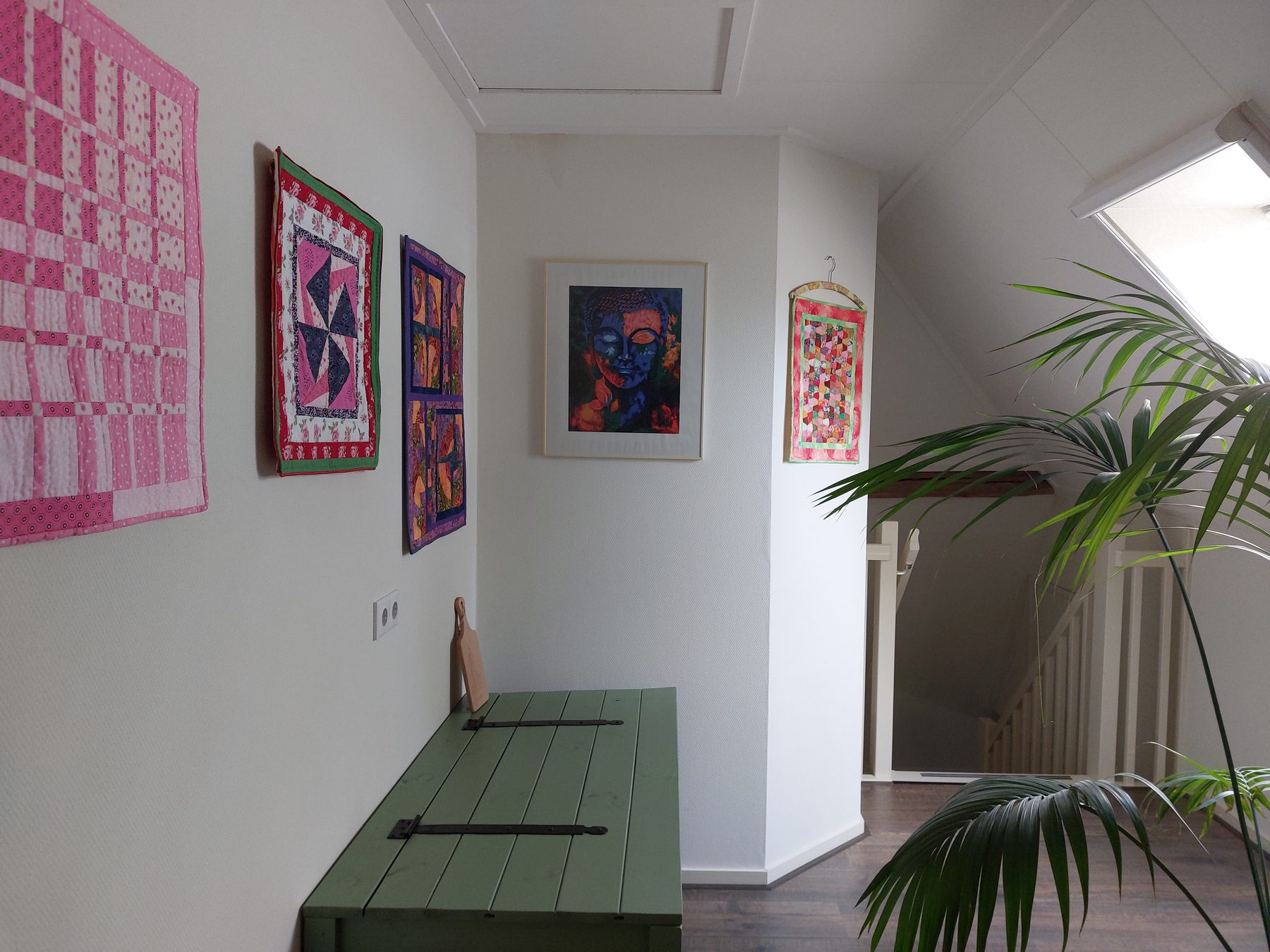 De overloop met zithoek en zelfgemaakte quilts aan de wand